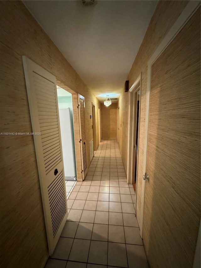 hallway with light tile patterned floors and wood walls