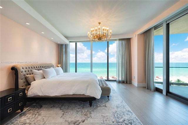 bedroom featuring hardwood / wood-style flooring, a water view, access to exterior, and a chandelier