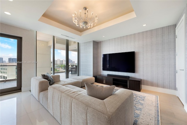 living room featuring an inviting chandelier, a raised ceiling, and french doors