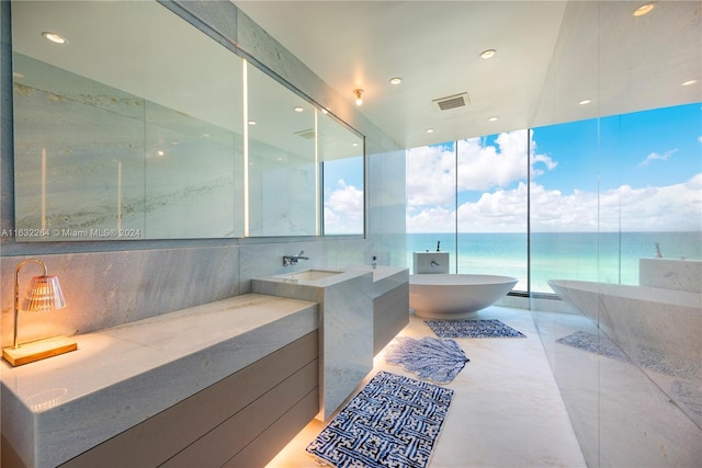 bathroom with a water view, vanity, a bath, a wall of windows, and tile patterned flooring