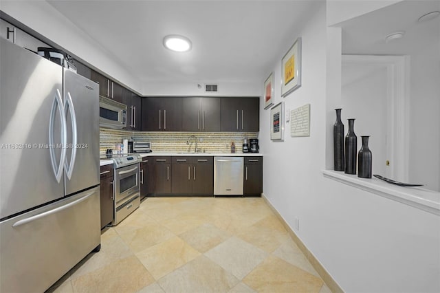 kitchen featuring appliances with stainless steel finishes, dark brown cabinets, sink, backsplash, and light tile patterned floors