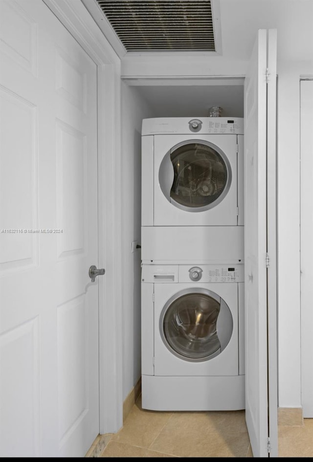 washroom with light tile patterned floors and stacked washer / drying machine