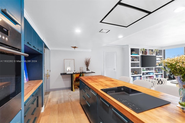 kitchen featuring blue cabinets, wooden counters, stainless steel oven, light wood-type flooring, and crown molding