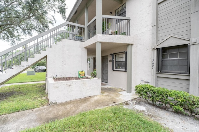 doorway to property featuring a yard and a balcony