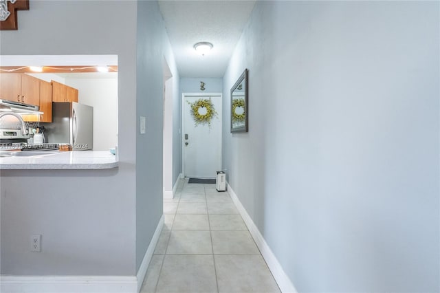 hallway with light tile patterned floors and a textured ceiling