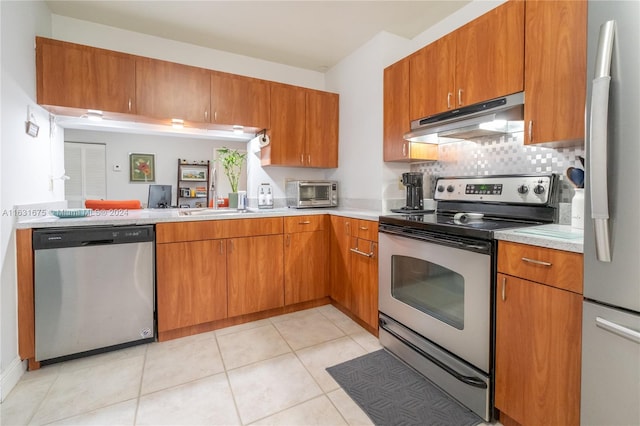 kitchen with light tile patterned floors, appliances with stainless steel finishes, and decorative backsplash