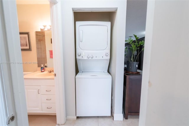 laundry area featuring sink, light tile patterned flooring, and stacked washer / drying machine