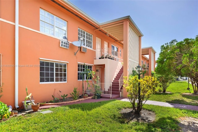 multi unit property with stairway, a front lawn, and stucco siding