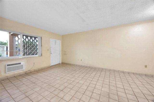 spare room with baseboards, a textured ceiling, and a wall mounted air conditioner