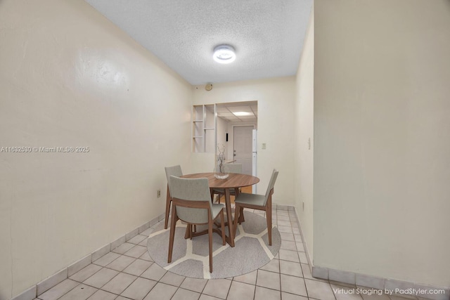 dining area with a textured ceiling, light tile patterned floors, and baseboards