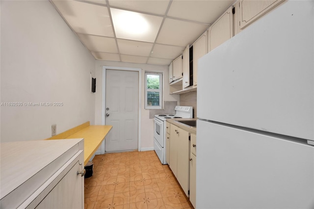 kitchen featuring light floors, light countertops, white cabinetry, white appliances, and a drop ceiling