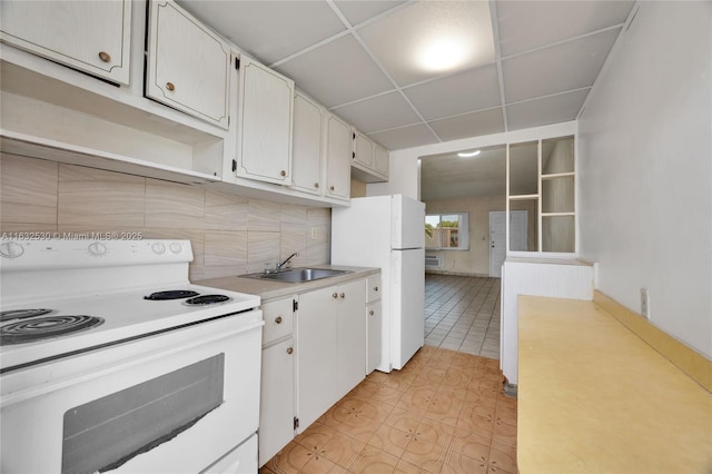 kitchen featuring white appliances, white cabinets, backsplash, light countertops, and a sink