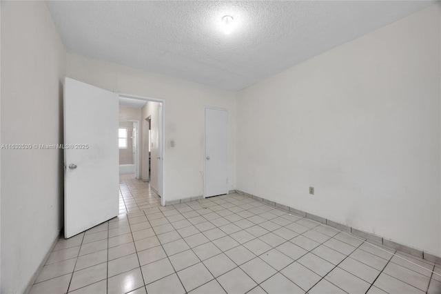 spare room with light tile patterned flooring and a textured ceiling