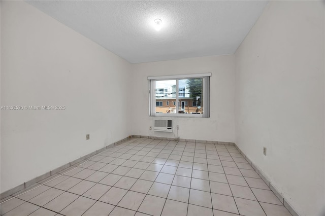 spare room featuring a wall unit AC, light tile patterned floors, and a textured ceiling