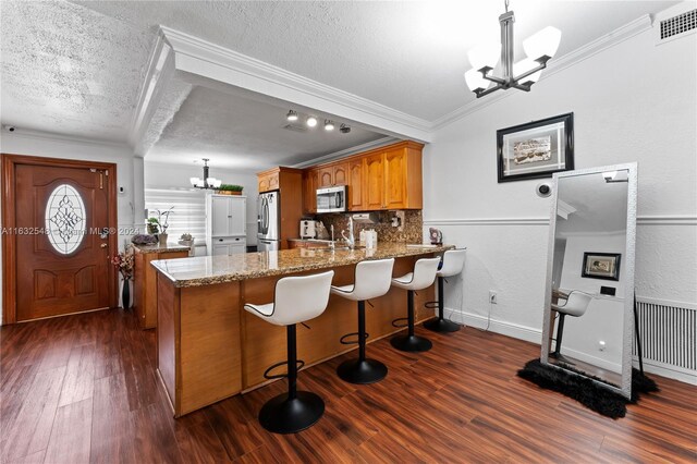 kitchen featuring stainless steel appliances, light stone counters, kitchen peninsula, a textured ceiling, and dark wood-type flooring