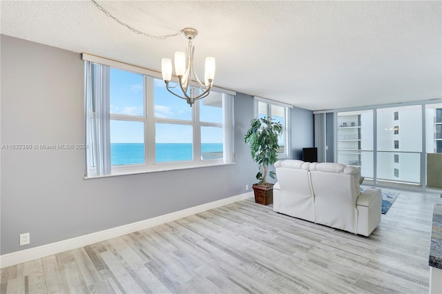 unfurnished living room with a textured ceiling, a chandelier, and light wood-type flooring