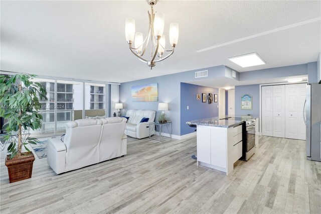 kitchen with light hardwood / wood-style flooring, stainless steel appliances, an inviting chandelier, decorative light fixtures, and stone countertops