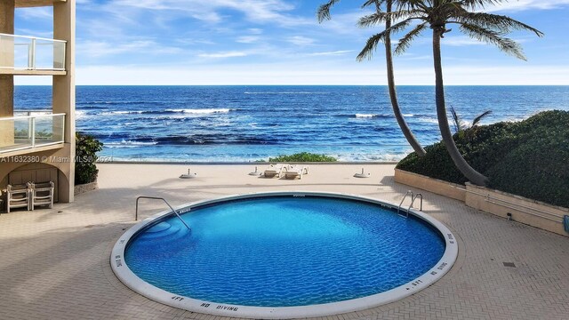 view of pool featuring a water view and a view of the beach