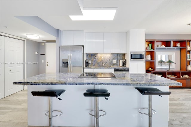 kitchen featuring a breakfast bar area, white cabinets, appliances with stainless steel finishes, decorative backsplash, and sink