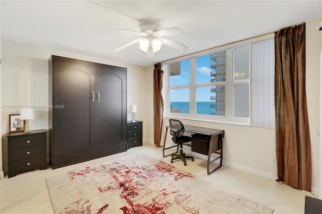 bedroom with a closet, a water view, ceiling fan, and light tile patterned floors