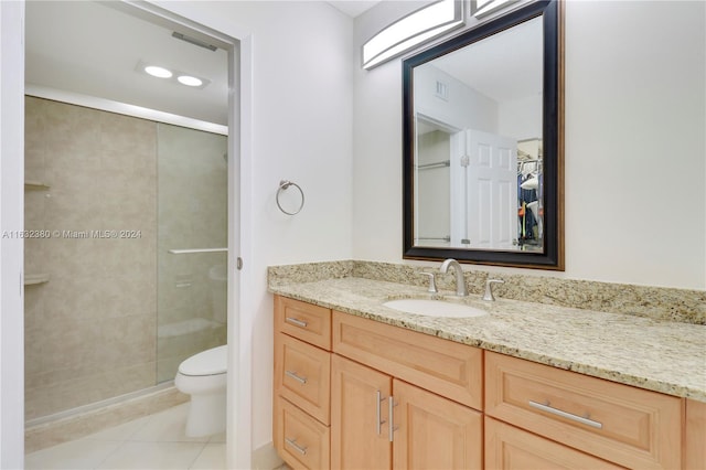 bathroom with vanity, a shower with door, toilet, and tile patterned floors