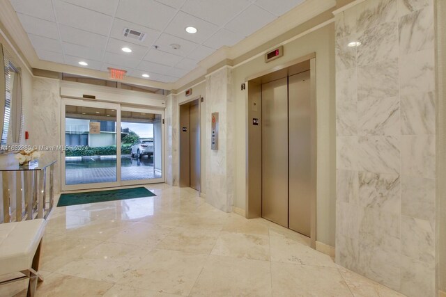 hallway with light tile patterned floors, a drop ceiling, and elevator