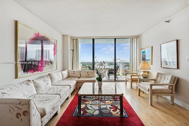 living room featuring a textured ceiling, floor to ceiling windows, and light hardwood / wood-style floors