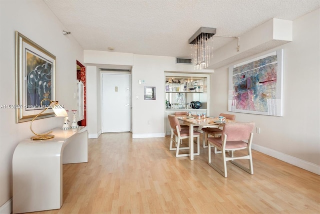 dining area with light wood-type flooring and a textured ceiling