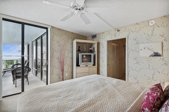 bedroom with a textured ceiling, ceiling fan, access to exterior, a wall of windows, and carpet