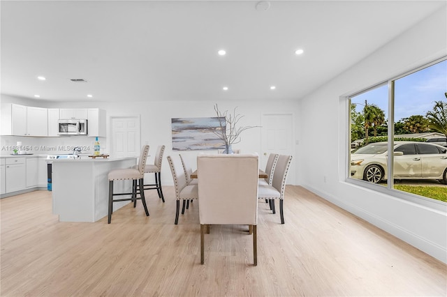 dining space with light wood-type flooring and a healthy amount of sunlight