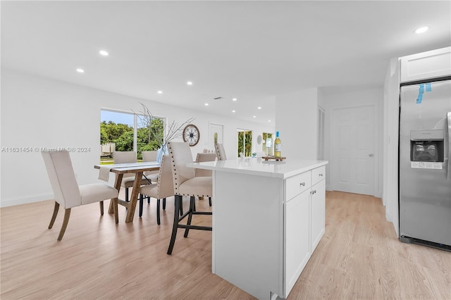 kitchen featuring a breakfast bar, white cabinetry, light hardwood / wood-style flooring, a center island, and stainless steel fridge