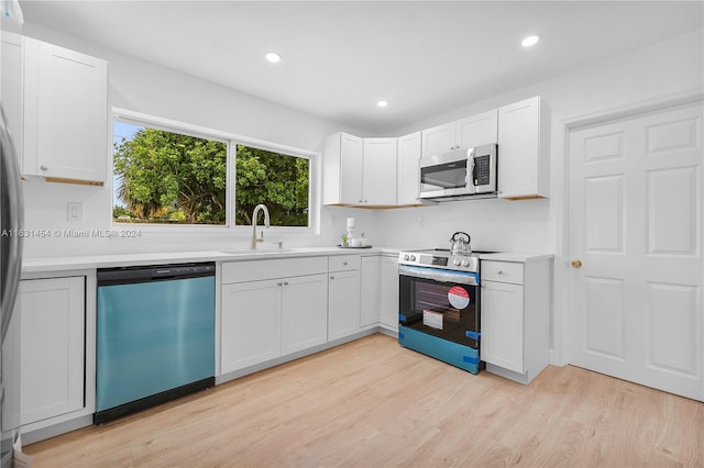 kitchen featuring appliances with stainless steel finishes, white cabinets, light wood-type flooring, and sink