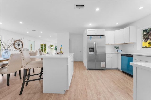 kitchen featuring light hardwood / wood-style flooring, white cabinets, stainless steel appliances, and a breakfast bar