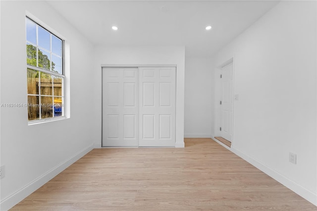 unfurnished bedroom with light wood-type flooring and a closet