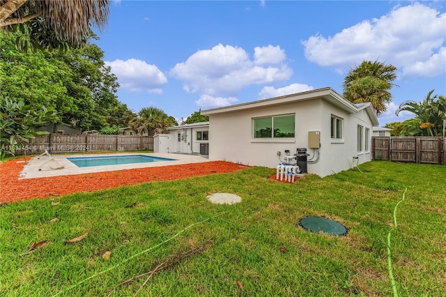 back of house with a yard and a fenced in pool