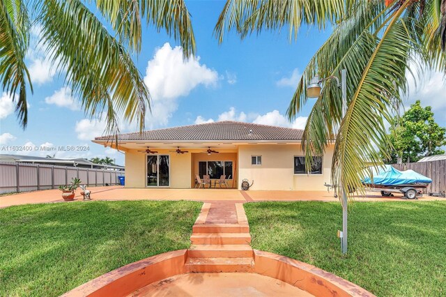 rear view of house with a patio, a yard, and ceiling fan