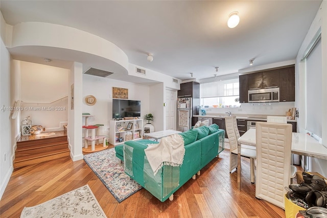 living room featuring visible vents, light wood-type flooring, and baseboards