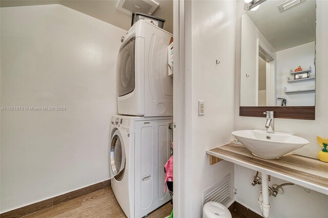 laundry room with stacked washer / dryer, hardwood / wood-style flooring, and sink