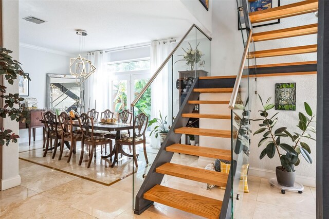 stairs with ornamental molding and an inviting chandelier