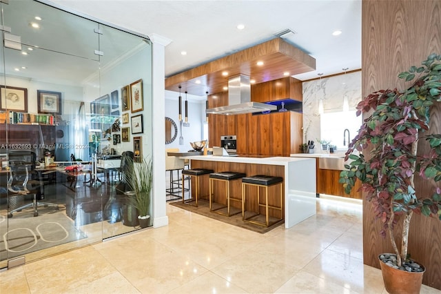 kitchen with ornamental molding, sink, kitchen peninsula, island range hood, and a breakfast bar area