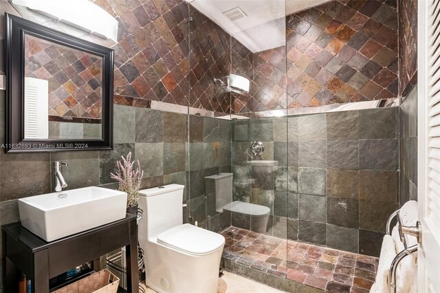 bathroom featuring tile walls, tiled shower, vanity, and toilet