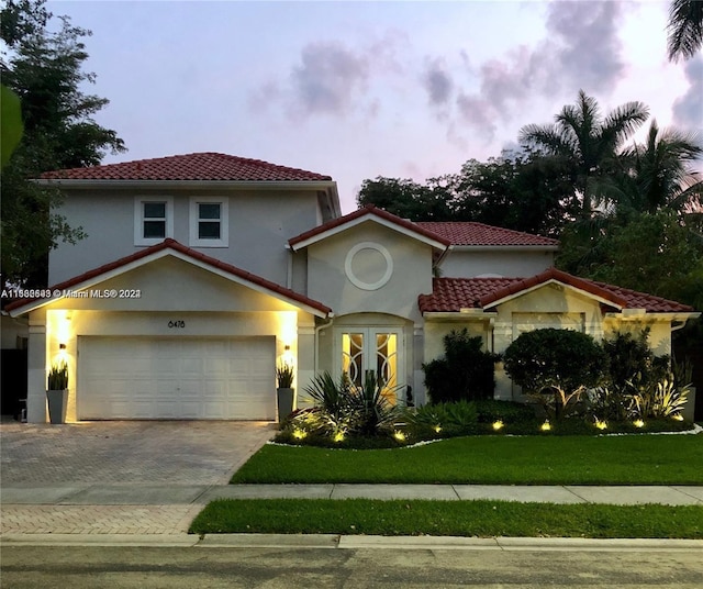 mediterranean / spanish-style home with a lawn and a garage