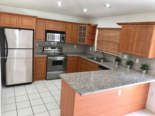 kitchen featuring tasteful backsplash, kitchen peninsula, sink, and appliances with stainless steel finishes