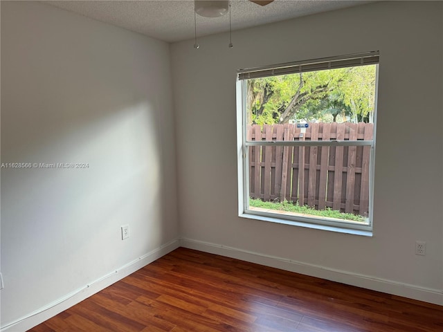 empty room with plenty of natural light, dark hardwood / wood-style floors, a textured ceiling, and ceiling fan