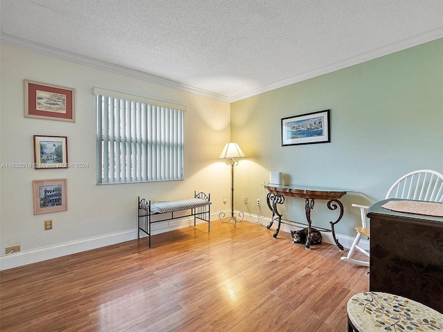 sitting room featuring hardwood / wood-style floors, ornamental molding, and a textured ceiling