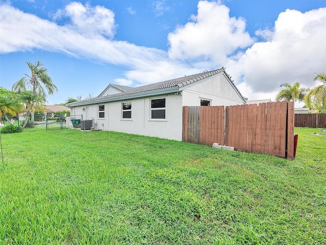 back of property featuring central AC and a lawn