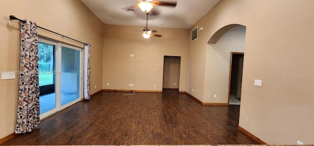 unfurnished room with ceiling fan, a high ceiling, and dark wood-type flooring