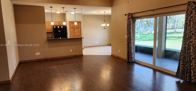 unfurnished living room featuring a notable chandelier and dark hardwood / wood-style floors