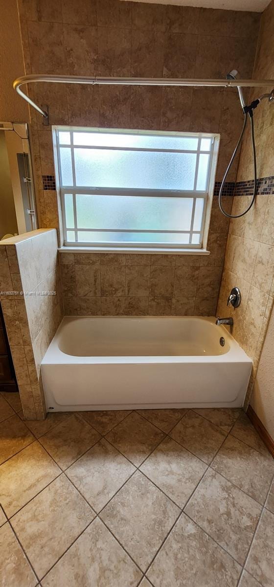 bathroom featuring tiled shower / bath, tile patterned floors, and a wealth of natural light