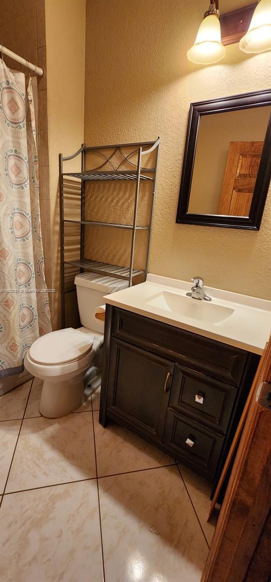 bathroom with toilet, tile patterned flooring, and vanity